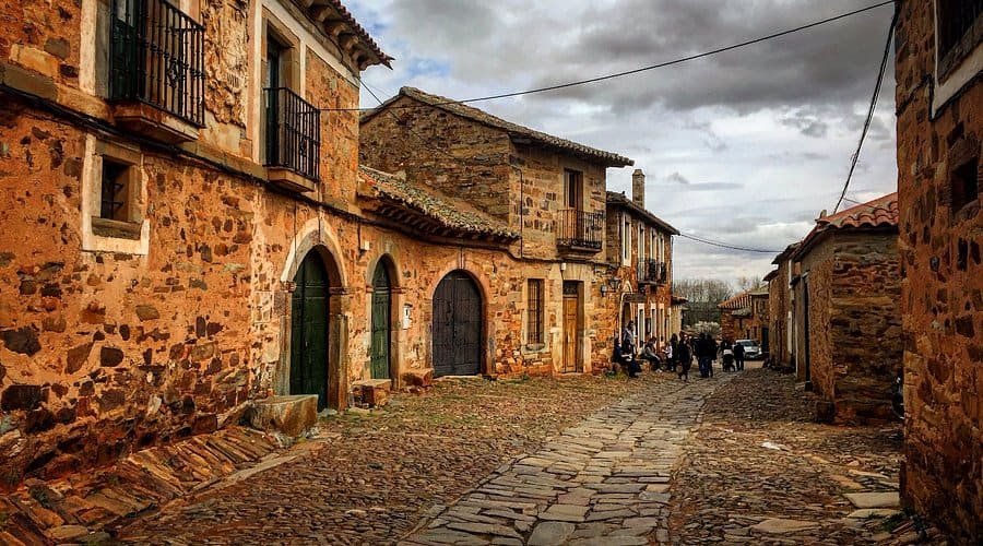 Calle principal de Castrillo de los Polvazares con casas de piedra rojiza y ambiente rústico - 5 pueblos bonitos de León