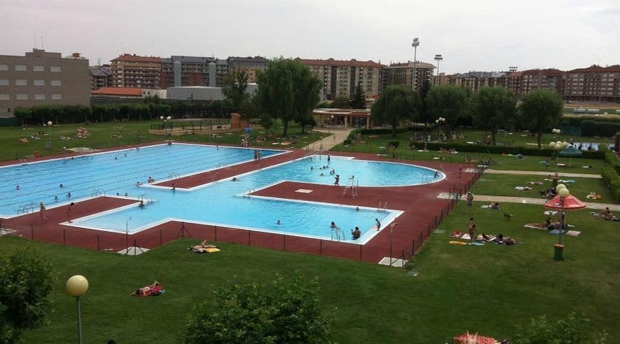 Piscina al aire libre en León con familias disfrutando del verano, actividad destacada para niños.